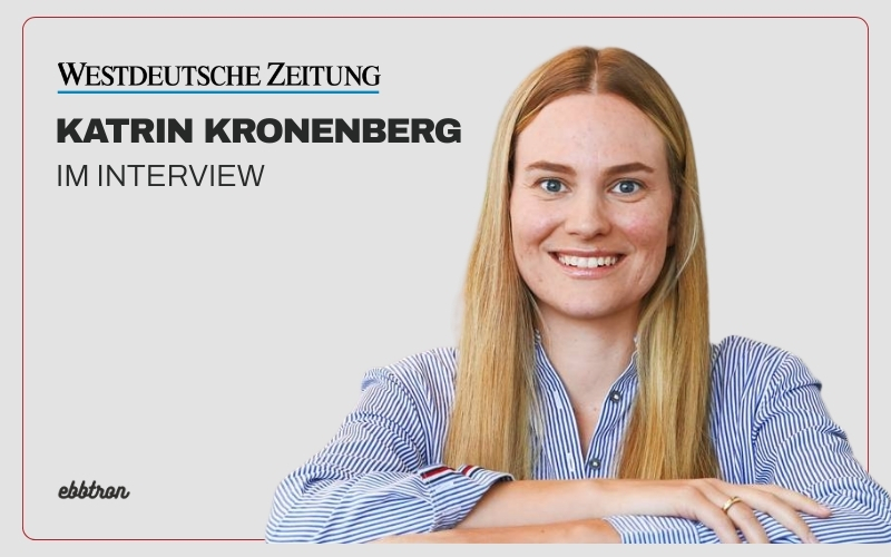 Porträtfoto von Katrin Kronenberg, Geschäftsführerin von Ebbtron, im Interview mit der Westdeutschen Zeitung. Sie sitzt lächelnd in einem blauen Hemd vor hellem Hintergrund, über ihr der Schriftzug ‚Westdeutsche Zeitung – Katrin Kronenberg im Interview‘.