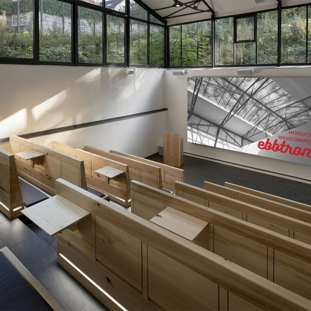 Auditorium im Ebbtron Solingen – moderner Hörsaal mit Holzbestuhlung, Leinwand und Tageslicht für Präsentationen, Vorträge und hybride Veranstaltungen.